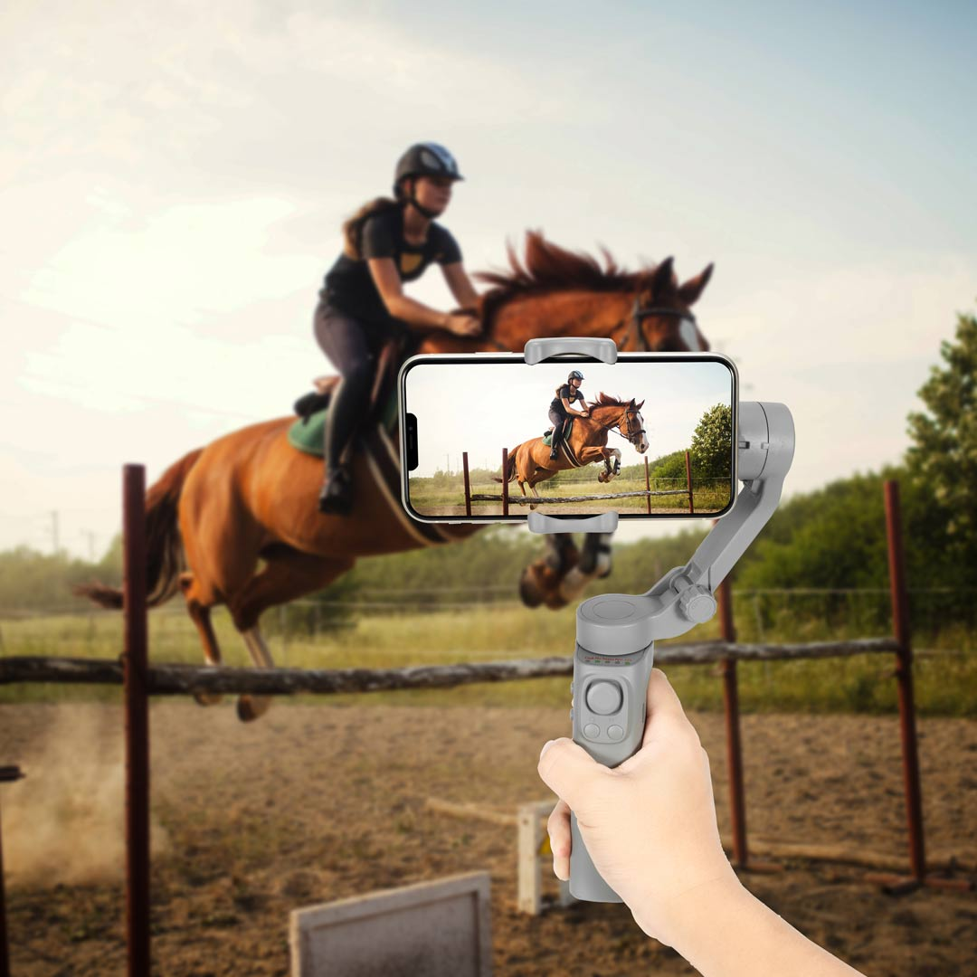 alt="woman horse riding  and taking video through gimbal"